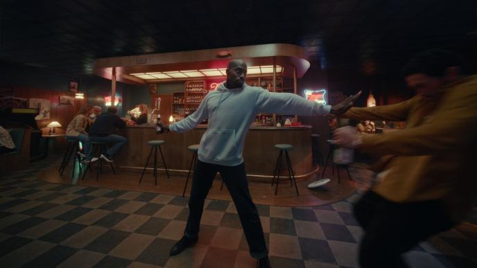 A man in a hoodie and jeans, dancing in a bar