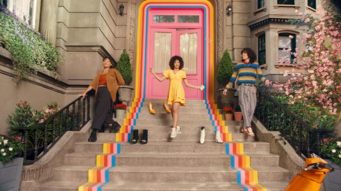 A young woman in a yellow dress leaves her home, accompanied by one person either side, going down some steps