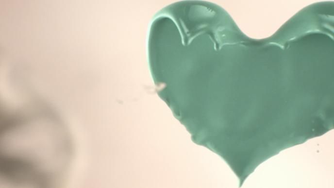 A green heart made of paint on a beige background.