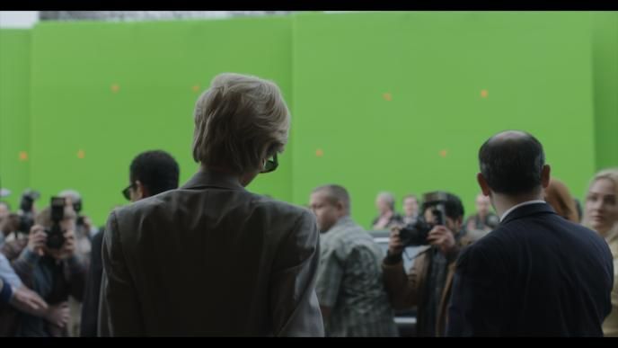 Elizabeth Debicki, playing Princess Diana walking towards paparazzi, with a green screen in the background, behind the screens