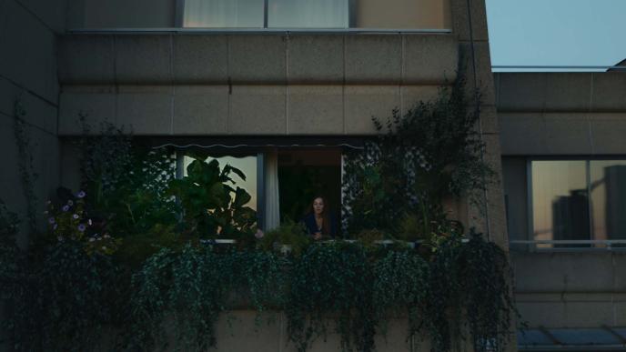 Concrete block of flats focusing on one balcony full of green plants 