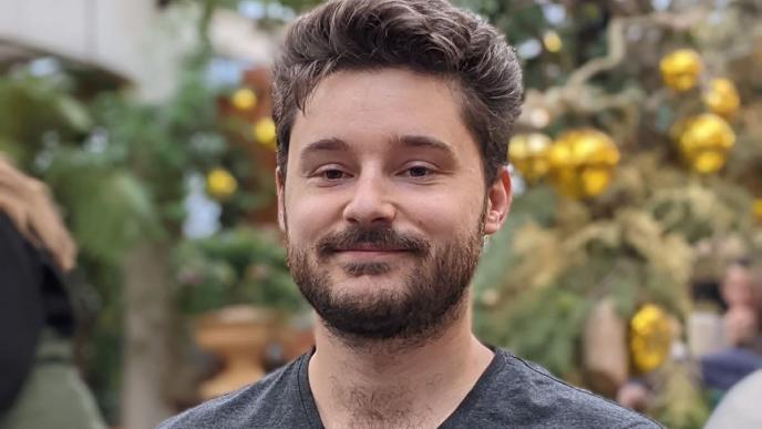 A photograph of a man with a lemon tree behind him.