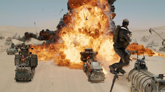 A scene from Mad Max Fury Road, a large tanker explodes surrounded by smaller vehicles