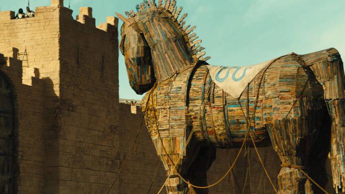A wooden Trojan horse outside the walls of a kingdom