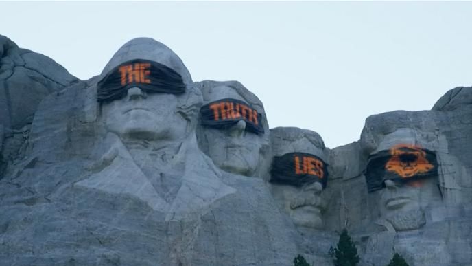 The presidents on Mount Rushmore blindfolded. The blindfolds are spray painted to create the phrase 'the truth lies'