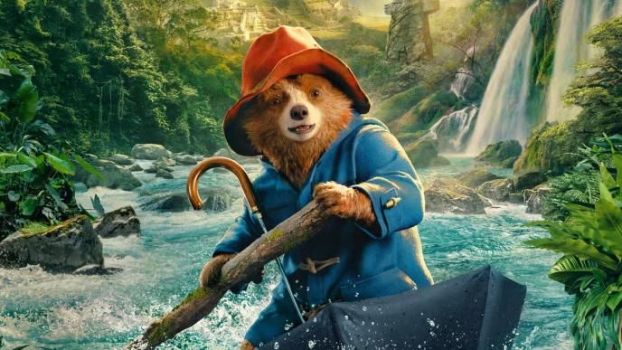 Paddington sits in an upturned umbrella, using it as a boat to sail down jungle rapids