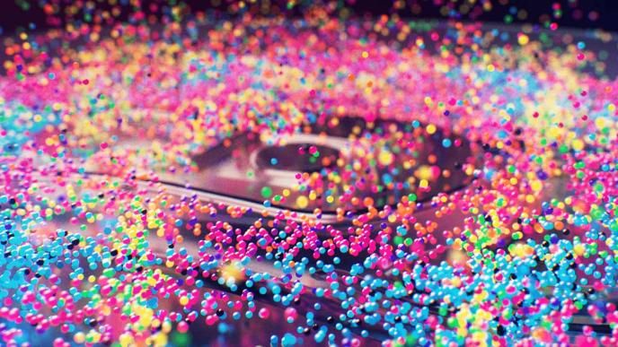 A speaker with animated multicoloured bubbles on it bouncing them up against a black background.