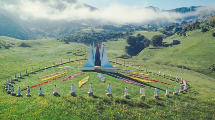 A CGI enhanced valley, with a central metal structure, surrounded by flowers
