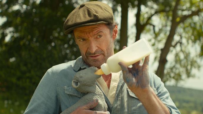 Hugh Jackman bottle feeds a plastic lamb in lieu of a real animal on the set of The Sheep Detectives