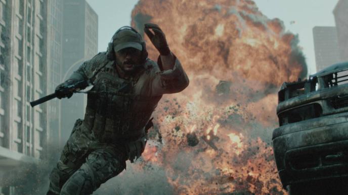 A soldier in tactical gear runs from a massive explosion in a city street, surrounded by CGI debris and damaged vehicles.