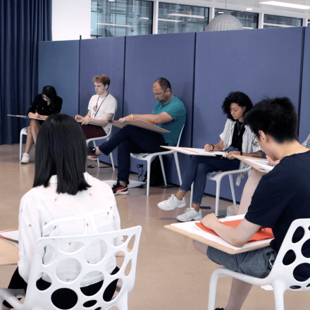 a group of people sitting at desk sketching on drawing pads