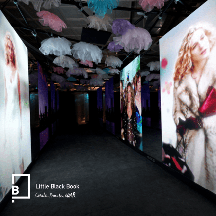 An image of the Carries Closet immersive event showing large screens featuring iconic outfits from Sex in the City.