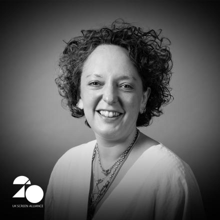 A black and white headshot of a woman with the UK Screen Alliance logo in the bottom left corner.