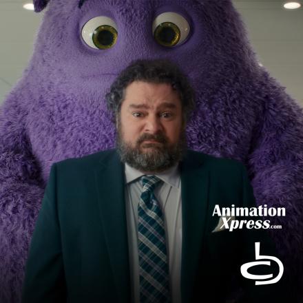 A large purple fluffy creature stood behind a man wearing a suit and tie. 