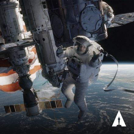 A woman astronaut floating outside of a space station above the earth, there is the Oscars logo in the bottom right corner.