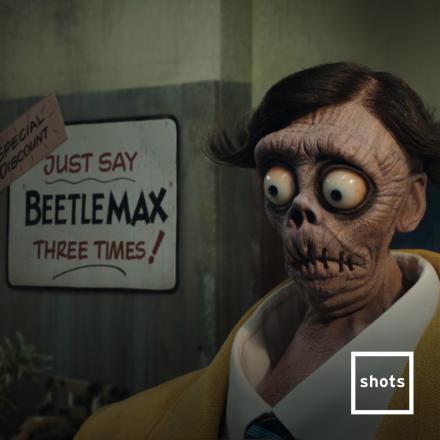 A character from Beetlejuice Beetlejuice in front of a sign that says BeetleMax sign. 